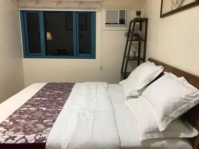 a bedroom with a large bed with a window at Partial Ocean View Opposite the US Embassy in Manila