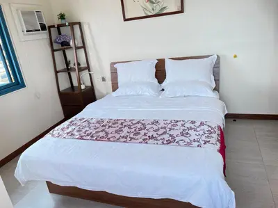 a bedroom with a white bed with a pink blanket on it at Partial Ocean View Opposite the US Embassy in Manila