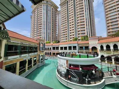 a boat in a river in a city with tall buildings at 12e Spacious Cozy Suite at The Venice Mall with FREE Parking and Washing Machine in Manila