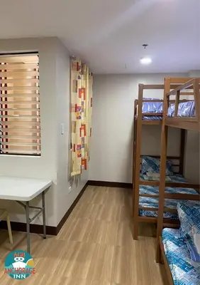 a room with bunk beds and a desk and a table at AGB Anchorage Inn, male dorm in Manila