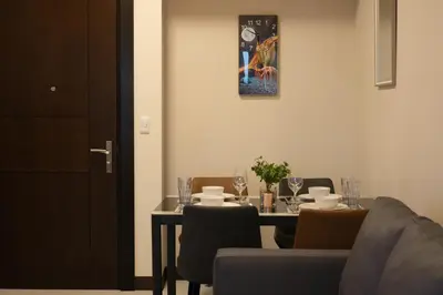 a dining room with a table with chairs and a painting at Cityscape View 2BR in Uptown BGC w 200mbps WiFi in Manila
