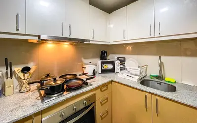 a kitchen with white cabinets and pots and pans on the stove at Cityscape View 2BR in Uptown BGC w 200mbps WiFi in Manila