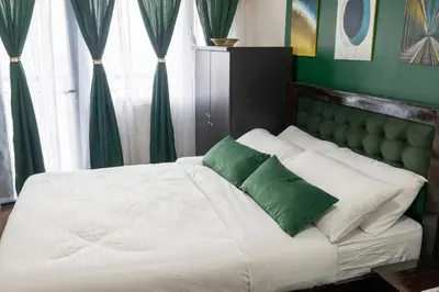 a bed with green and white pillows in a bedroom at Royal Victorian Studio in Makati in Manila