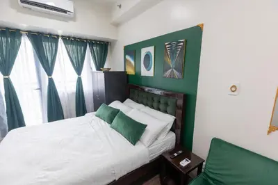 a bedroom with a white bed with green accents at Royal Victorian Studio in Makati in Manila