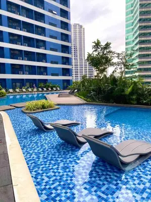 a swimming pool with lounge chairs in a building at Royal Victorian Studio in Makati in Manila