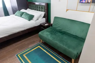 a room with a bed and a green couch at Royal Victorian Studio in Makati in Manila