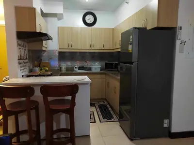 a kitchen with a black refrigerator and wooden cabinets at ALEA RESIDENCES Condo near Airport and MOA! Cozy Place with Main street and Manila Bay view in Manila