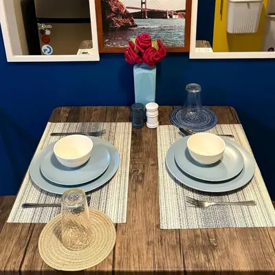 a table with two plates and a vase with red roses at Casas Reales Staycation & Rentals in Biñan