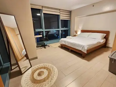 a bedroom with a bed and a large window at One Uptown BGC Modern & Spacious, Great Location, 200mbps & washer in Manila