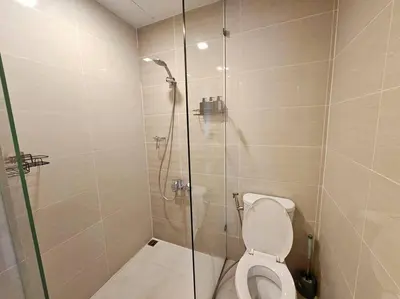 a bathroom with a toilet and a glass shower at One Uptown BGC Modern & Spacious, Great Location, 200mbps & washer in Manila