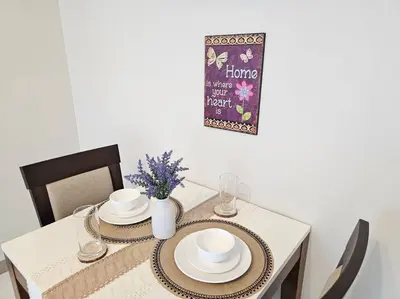 a table with two plates and a vase with flowers on it at One Uptown BGC Modern & Spacious, Great Location, 200mbps & washer in Manila
