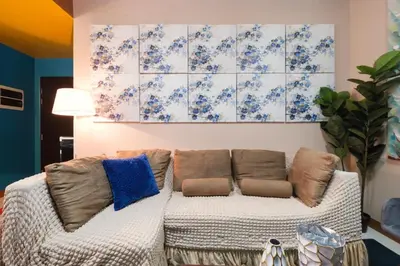 a living room with a couch and a painting on the wall at Family Staycation, Greenbelt Hamilton, Isabel's Makati Rooms in Manila