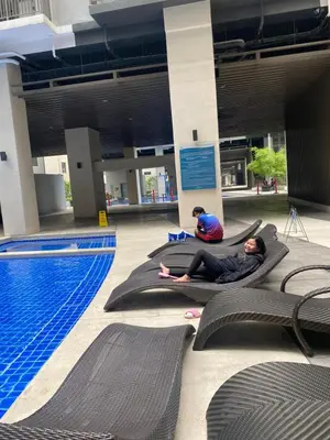two people laying on mats next to a swimming pool at Cozyhome by LV & SG - S residences MOA PASAY unit condo in Manila