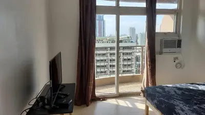 a bedroom with a window with a view of a city at Hospital ng Manila front delux le mirage de malate in Manila