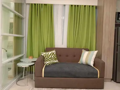 a couch in a living room with green curtains at OASIS CHIC By THE BAY PASAY CITY Near Mall of Asia in Manila