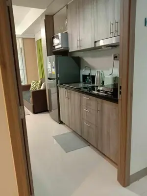 a kitchen with wooden cabinets and a couch in a room at OASIS CHIC By THE BAY PASAY CITY Near Mall of Asia in Manila