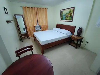 a bedroom with a bed and a chair and a mirror at Lawton Residences Studio Room 2F in Manila