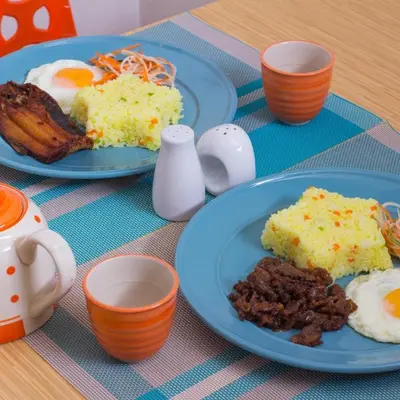 two plates of food on a table with eggs and meat at Starlight Bed and Breakfast in Manila