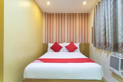 a bedroom with a white bed with red pillows at Starlight Bed and Breakfast in Manila