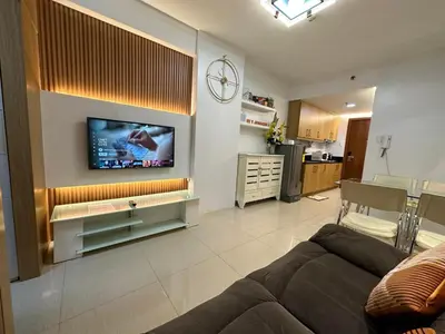 a living room with a couch and a tv on a wall at Shell Residences, Pasay near NAIA MOA SMX PICC in Manila