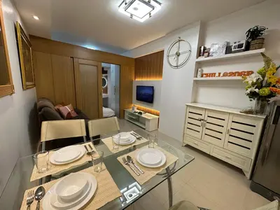 a living room with a glass table with plates on it at Shell Residences, Pasay near NAIA MOA SMX PICC in Manila