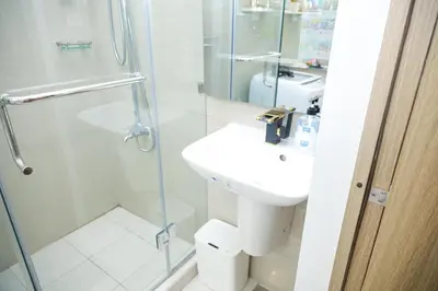 a white bathroom with a sink and a shower at Shore2 Luxurious & Homely Suite near MOA in Manila