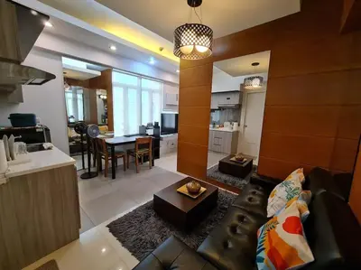 a living room and kitchen with a couch and a table at Beautiful Condo in BGC Taguig - McKinley in Manila