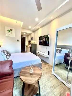 a bedroom with a bed and a couch and a table at Stanford Suites 3 in Silang