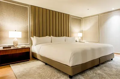 a bedroom with a large white bed and two lamps at Brittany Hotel Villar City in Cavite
