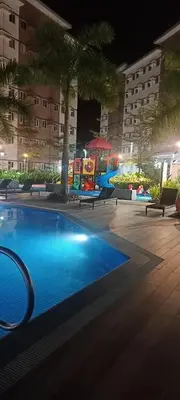 a swimming pool at night with palm trees and buildings at Happy Stays B - 300mbps - 65