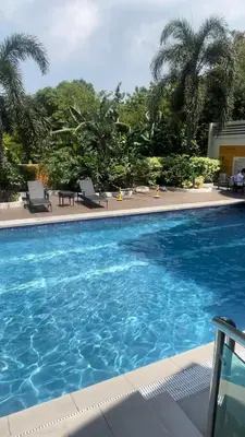 a large blue swimming pool with chairs and palm trees at 2-Bed Apartment in Near Airport Paranaque in Manila