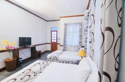 a room with two beds and a tv and a desk at Villa Jhoana Resort in Angono