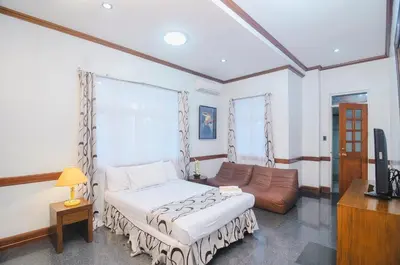 a bedroom with a bed and a couch and a television at Villa Jhoana Resort in Angono