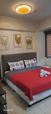 a bedroom with a large bed with a red blanket at Airport staycation @MRMCONDOTEL in Manila