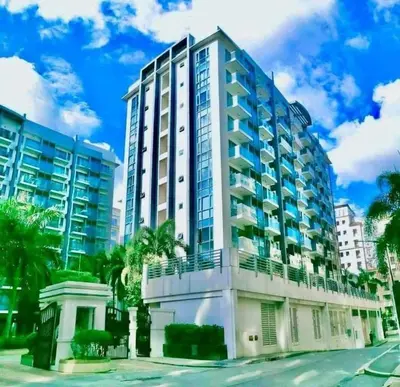 a building on a street with palm trees at Airport staycation @MRMCONDOTEL in Manila