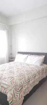 a bed with a colorful comforter and a pillow at 2BR Irish Luck Holiday Apartment in Manila