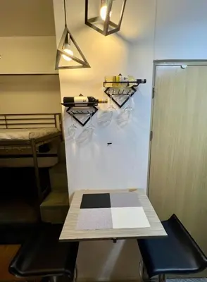 a room with a table and a bed and shelves at H&H at Grace Residences in Manila