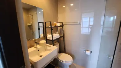 a bathroom with a sink and a toilet and a mirror at BGC Uptown Mall Suite in Manila