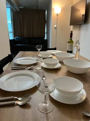 a wooden table with white plates and wine glasses at BGC Uptown Mall Suite in Manila