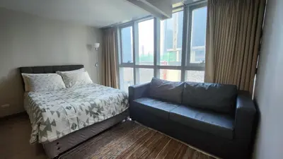 a bedroom with a couch and a bed and a window at BGC Uptown Mall Suite in Manila