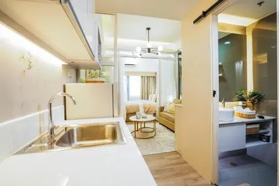 a kitchen with a sink and a living room at Air Residences Makati with Sunset View in Manila