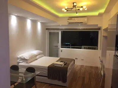 a bedroom with a bed and a large window at Cozy35sqm w parking balcony Wifi/Netflix near Mall in Manila