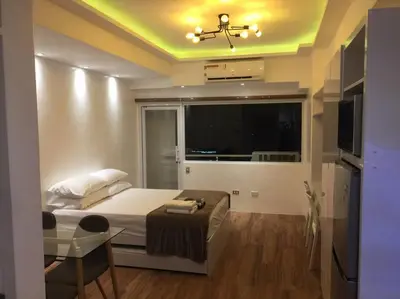 a bedroom with a bed and a large window at Cozy35sqm w parking balcony Wifi/Netflix near Mall in Manila
