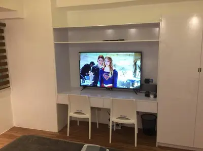 a room with a television on a wall with chairs at Cozy35sqm w parking balcony Wifi/Netflix near Mall in Manila