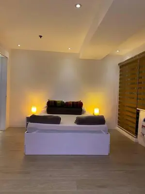 a bedroom with a bed with two lamps on it at Cozy60sqm 1BR balcony/prking/Wifi/Ntflix near Mall in Manila
