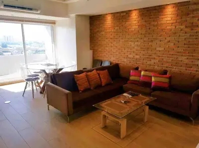 a living room with a couch and a brick wall at Cozy60sqm 1BR balcony/prking/Wifi/Ntflix near Mall in Manila
