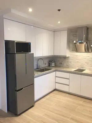 a kitchen with white cabinets and a stainless steel refrigerator at Cozy60sqm 1BR balcony/prking/Wifi/Ntflix near Mall in Manila