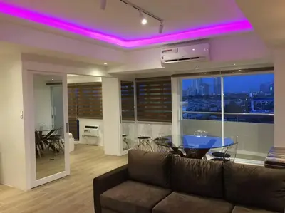 a living room with a couch and a table with purple lights at Cozy60sqm 1BR balcony/prking/Wifi/Ntflix near Mall in Manila