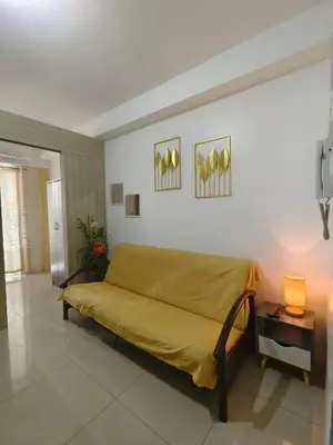 a couch in a room with a yellow blanket at METRO STAYCATION PASAY MALL OF ASIA in Manila