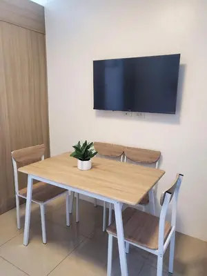 a wooden table with chairs and a tv on a wall at METRO STAYCATION PASAY MALL OF ASIA in Manila